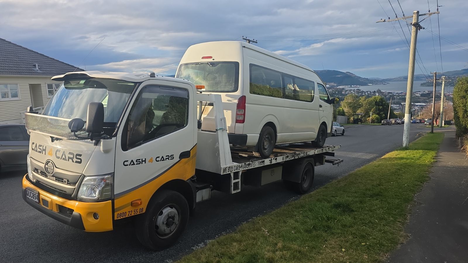 Cash 4 Cars tow truck collecting a van with harbour views behind